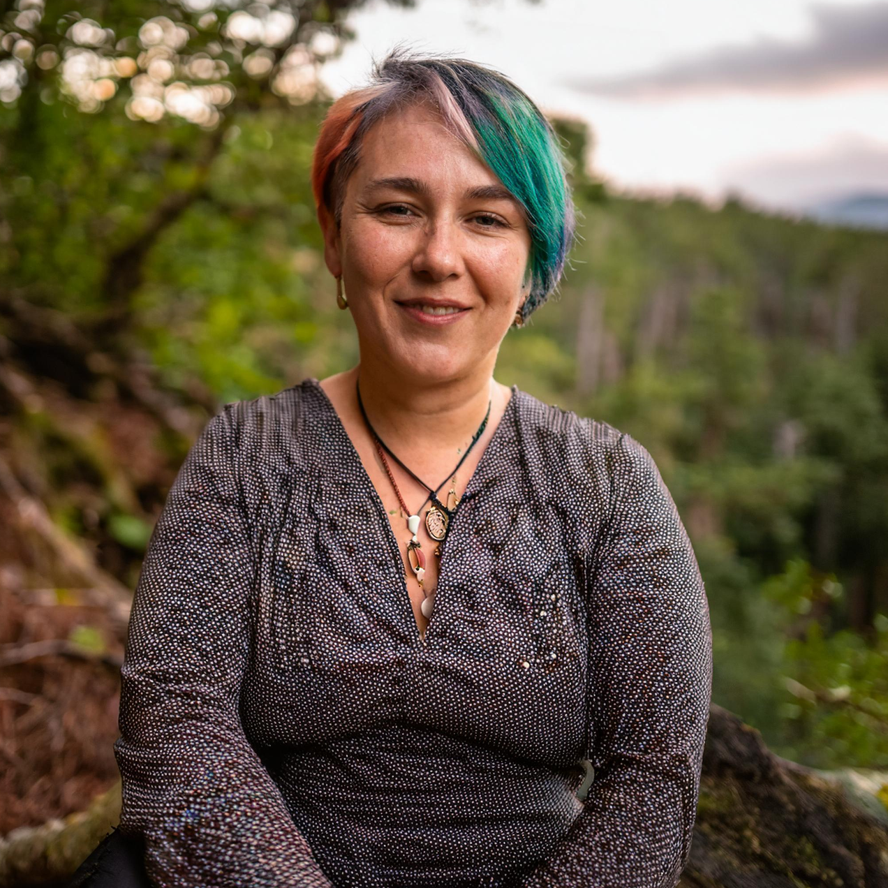 Photo of a woman with colourful hair sat outdoors