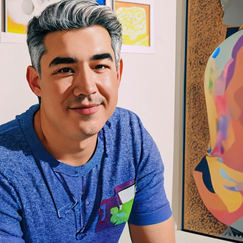 Photo of a man dressed casually and smiling sat indoors