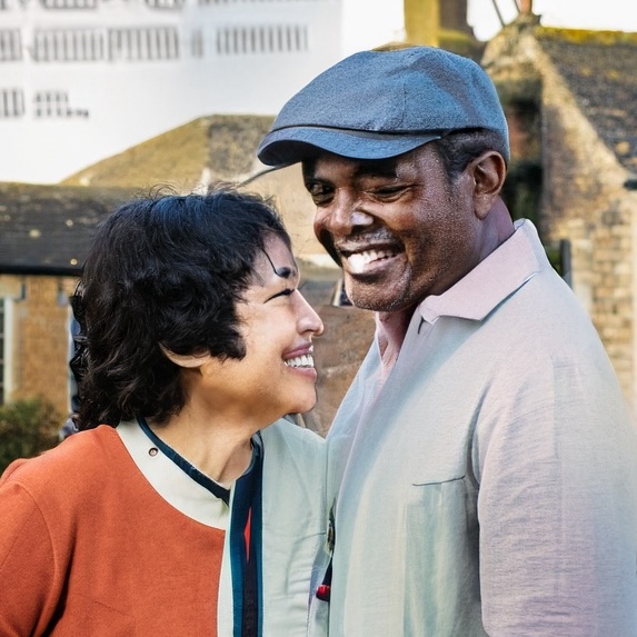 Photo of a smiling couple stood in front of a house